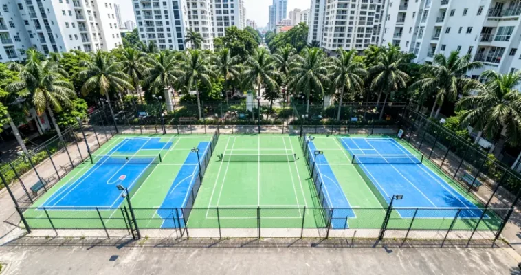 Cụm sân pickleball ngoài trời mặt sơn acrylic xanh, có hàng rào và đèn chiếu sáng giữa khu chung cư ở TP.HCM